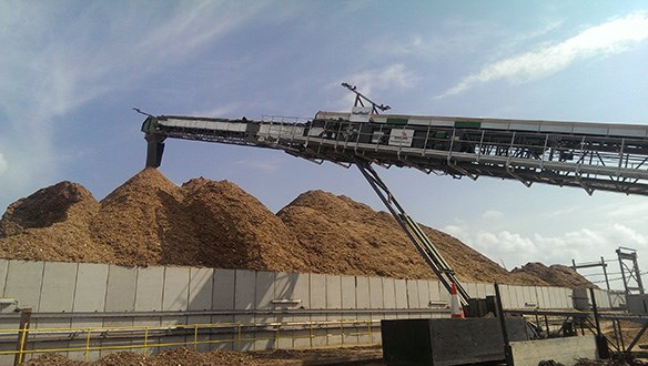 Radial conveyor stockpiling woodchips