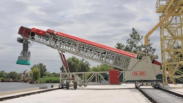 Rail mounted parallel travel fed from overhead conveyor